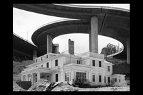 A crumbling house in the middle of a construction site and highway