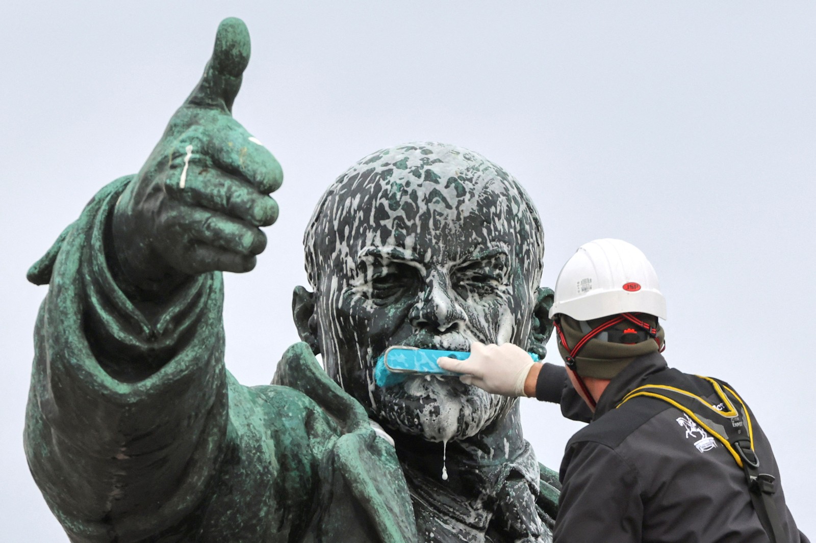 A worker scrubs the mouth of a statue of Lenin.