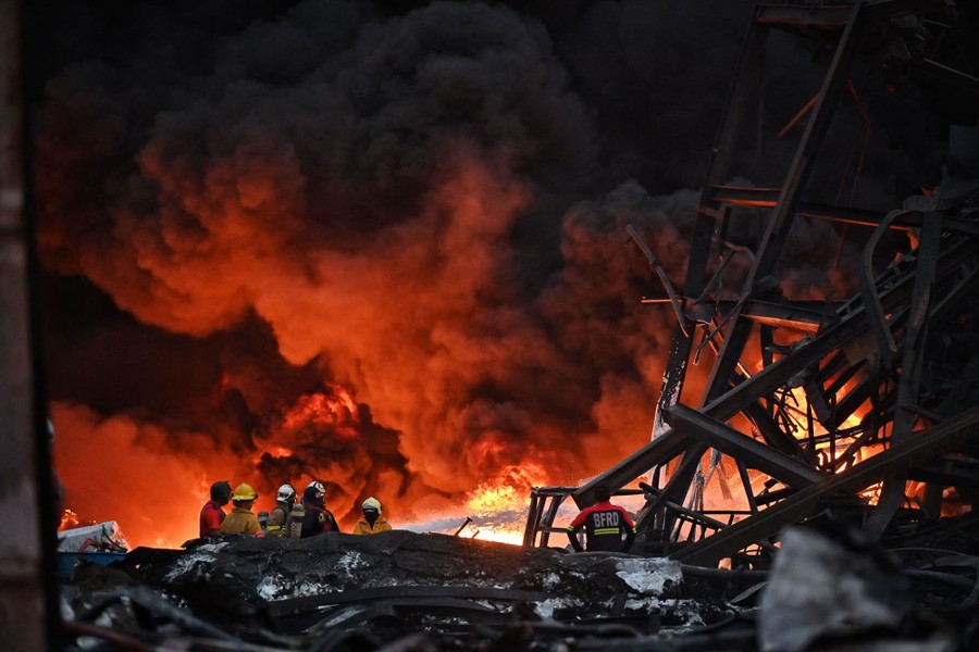 Several firefighters work at the site of a burning factory.
