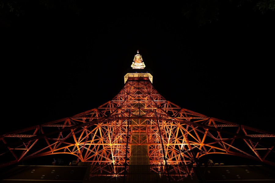 A night view, looking up toward a tall illuminated metal tower.