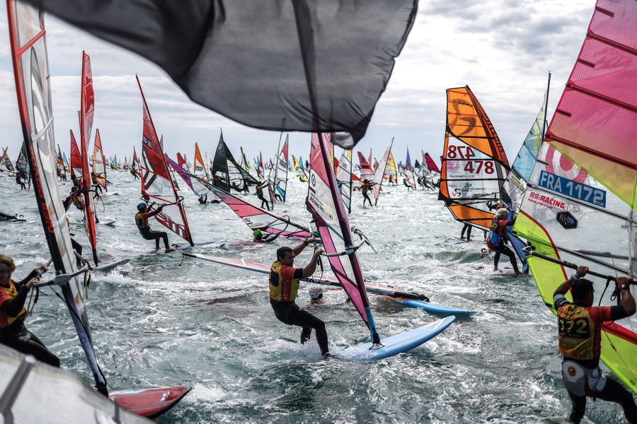 Dozens of windsurfers sail past in a race.