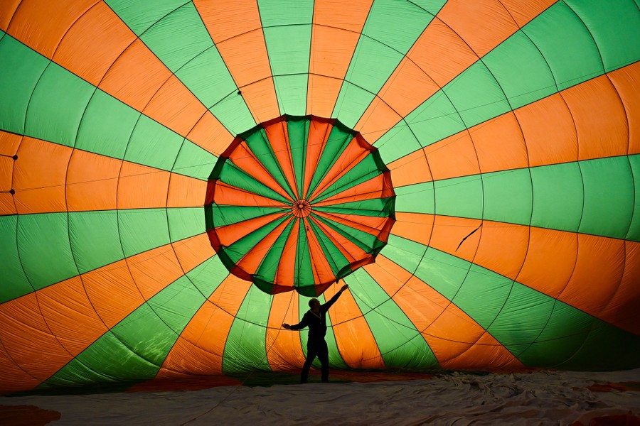 A person reaches out their arms inside a partially inflated hot-air balloon.