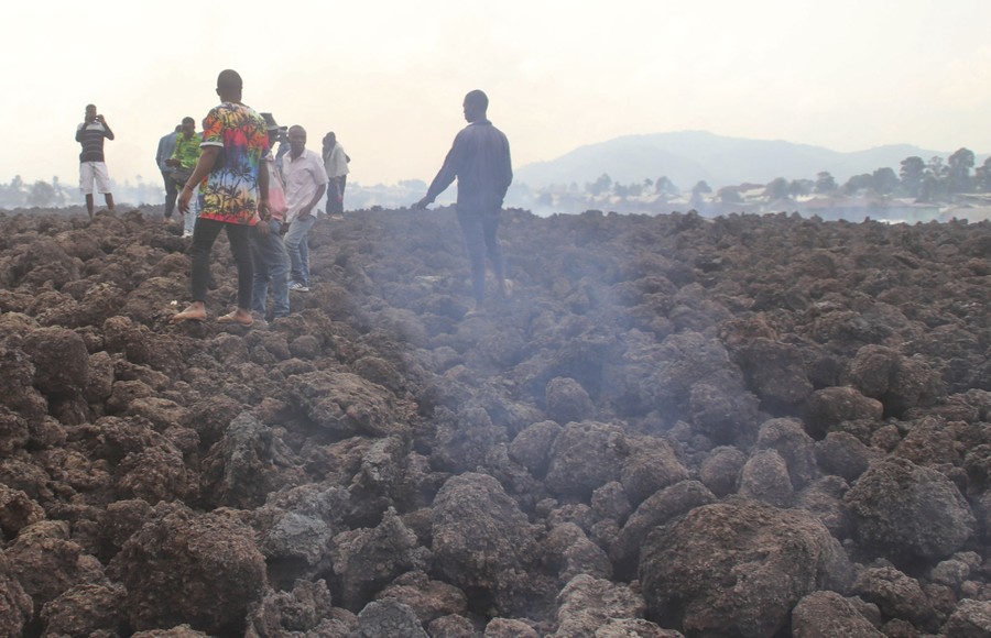 People walk on still-smoking lava rocks.