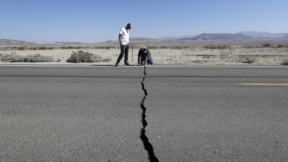 Two men examine a crack in Highway 178 caused by the recent earthquakes in Ridgecrest, California.