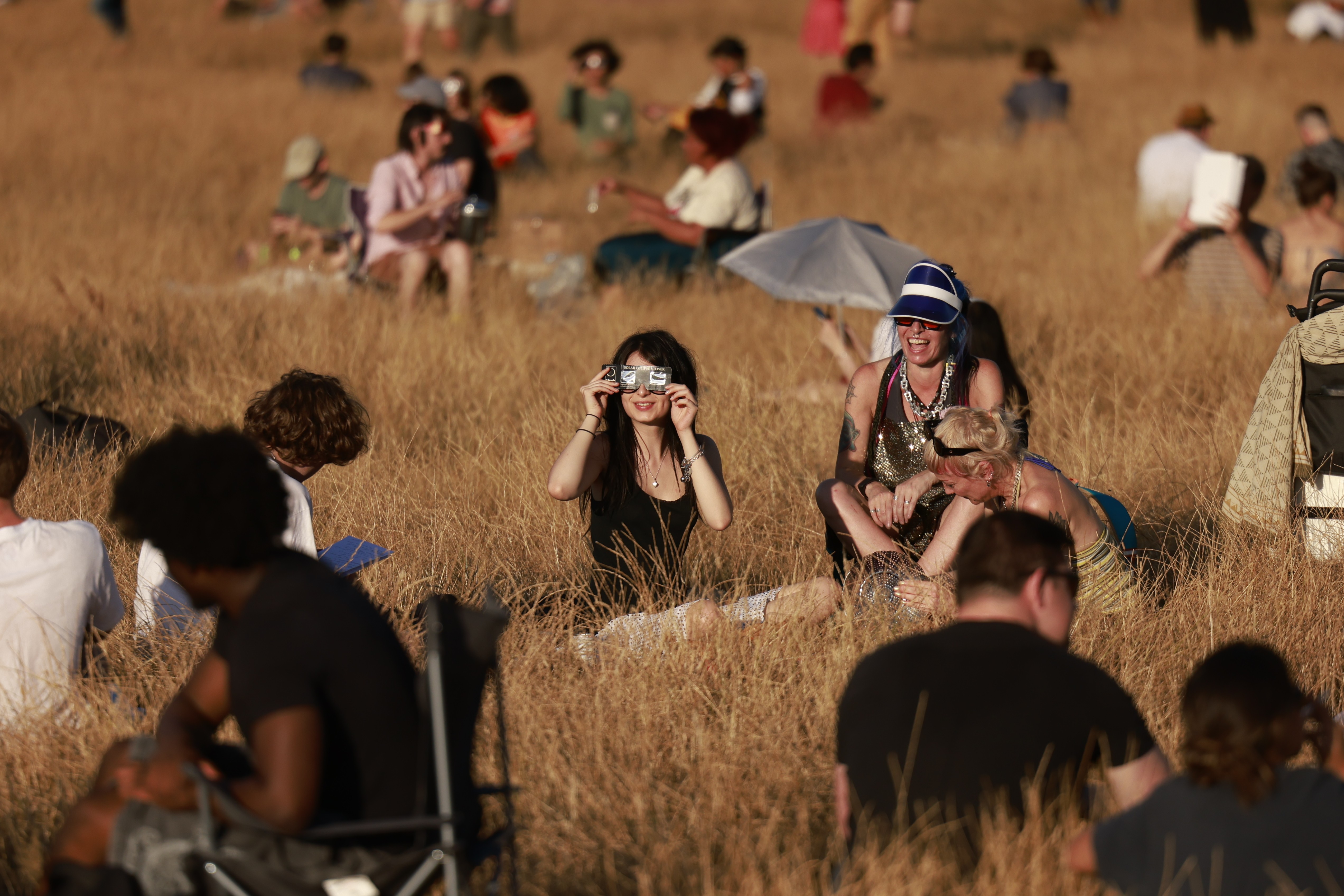 People with eclipse glasses gather in a field.