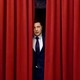 Volodymyr Zelensky as the fictional president of Ukraine, peeking out from behind red curtains, in "Servant of the People"