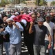 a color photograph of pallbearers carrying the body of Odeh Muhammad al-Hathalin