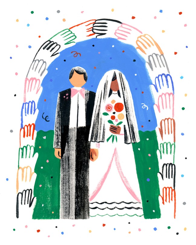 A bride and groom stand under an arch made of hands holding each other