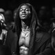black-and-white photo of shirtless Lil Nas X wearing a black coat
