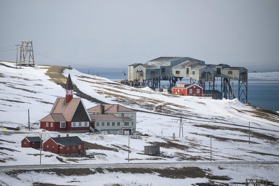 Several old industrial buildings and a church on a hillside