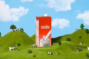 A big carton of milk in a green field amidst trees and cows.