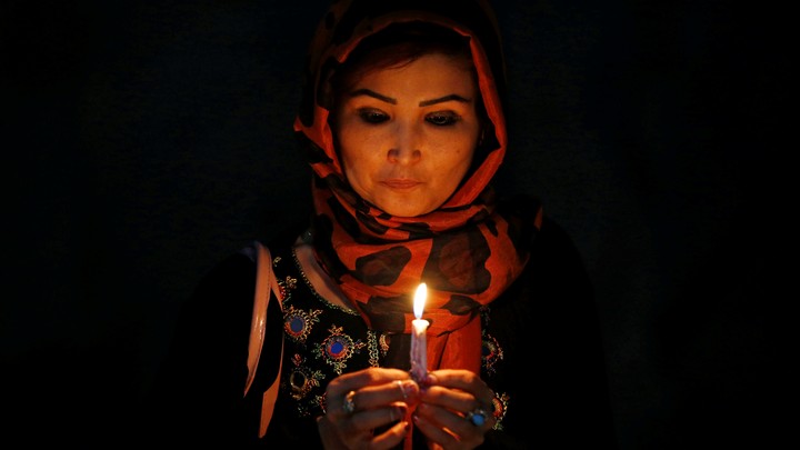 A woman holds a lit candle for the victims of Wednesday's blast in Kabul, Afghanistan.