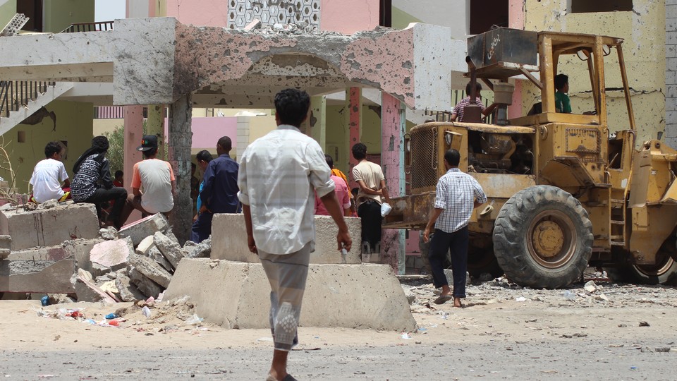 People gather near the site of a suicide car bombing Monday in Aden, Yemen