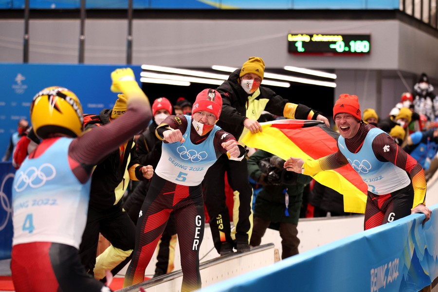 Several athletes from Germany celebrate at the end of a luge track.