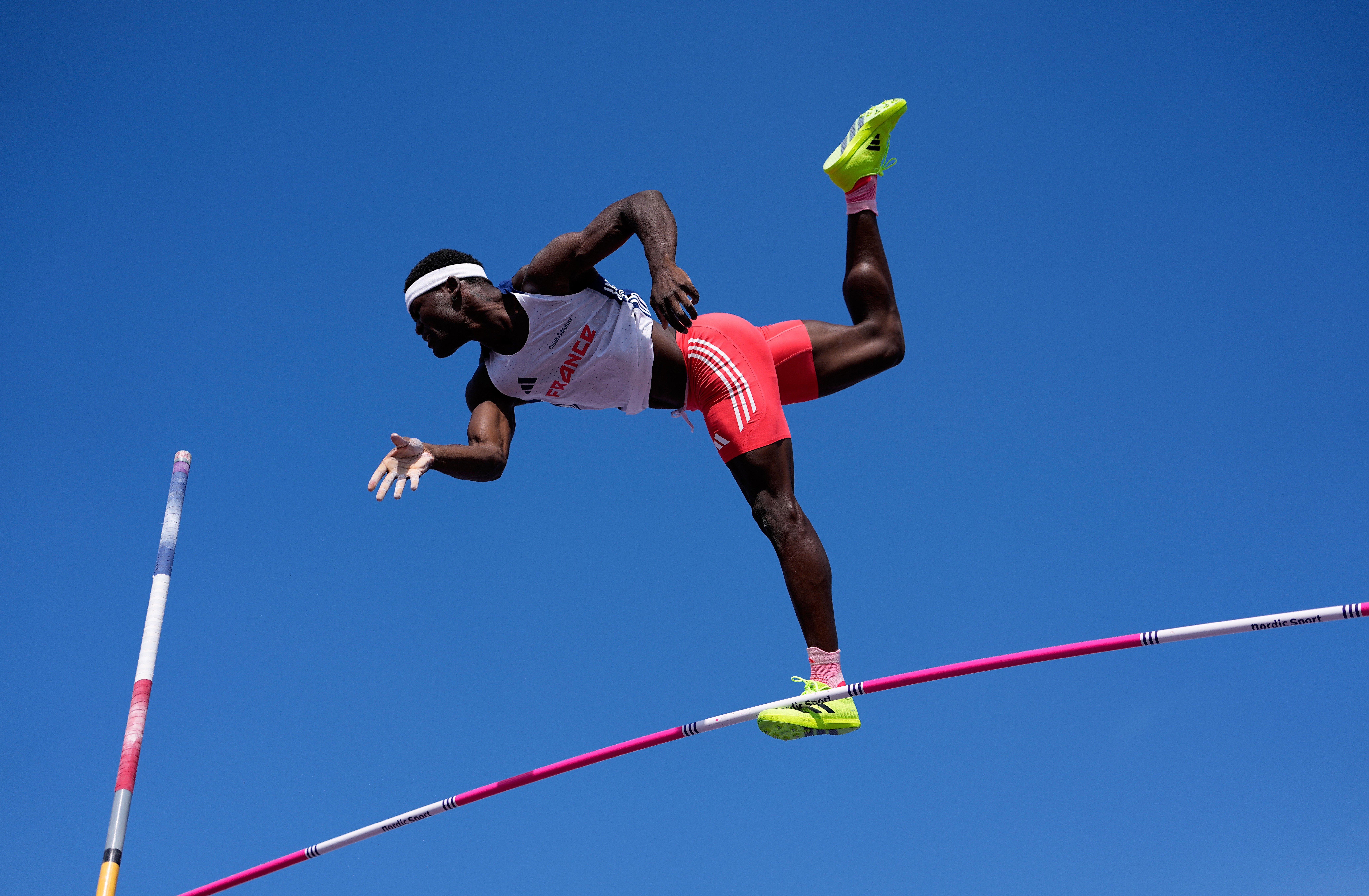A track athlete falls through the air after missing a pole vault attempt.