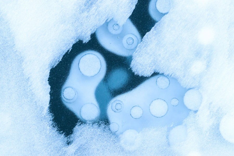 An aerial view of large air bubbles trapped in lake ice