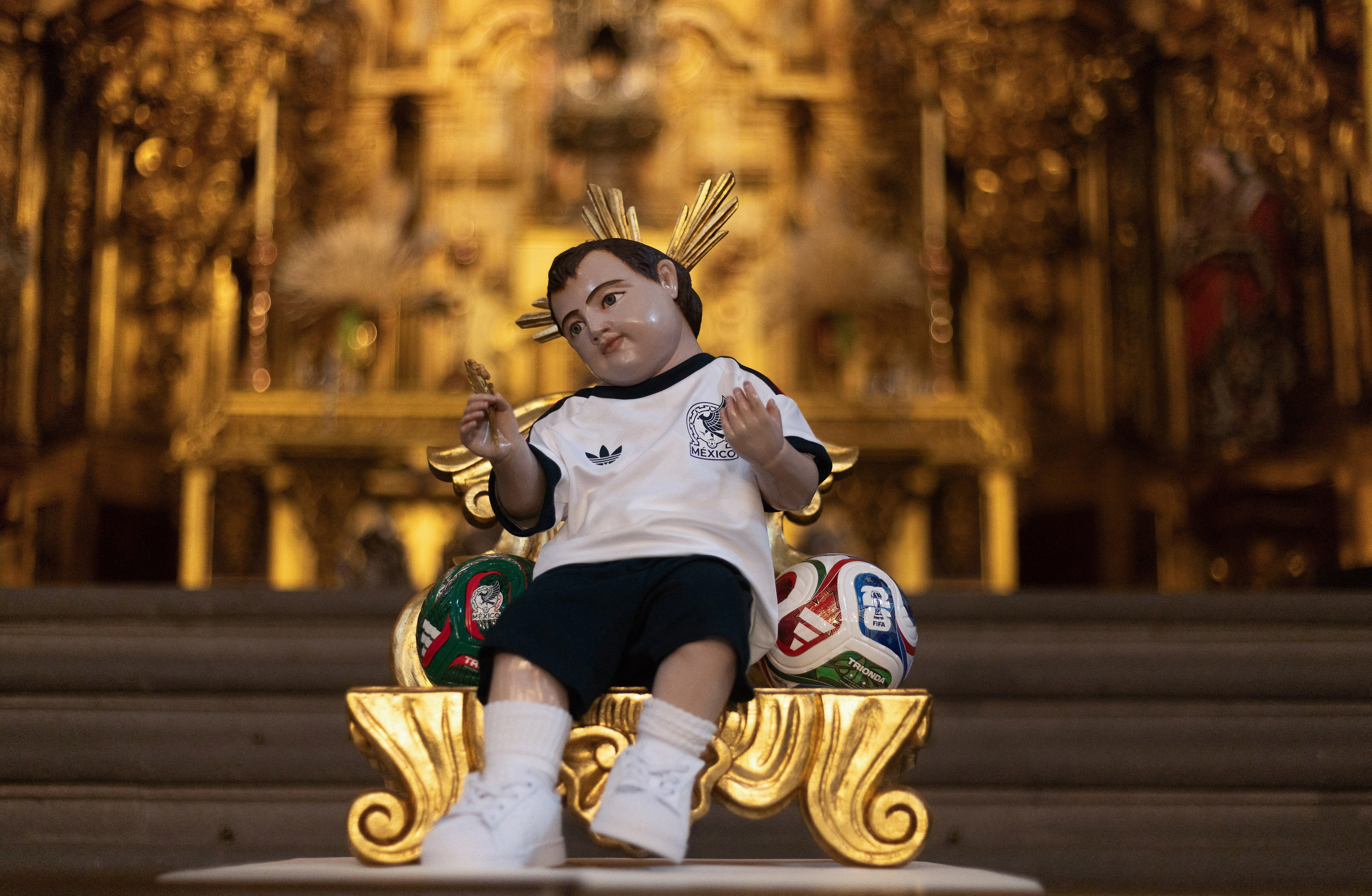 A figurine of the baby Jesus in a cathedral is dressed in a jersey of the Mexican national team.