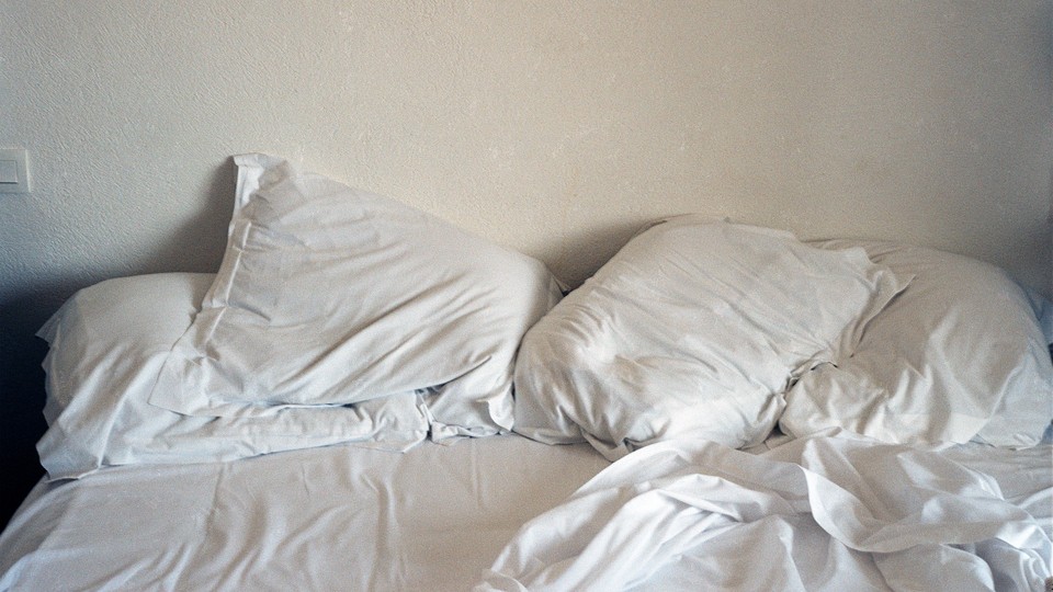 A picture of a bed with rumpled white sheets