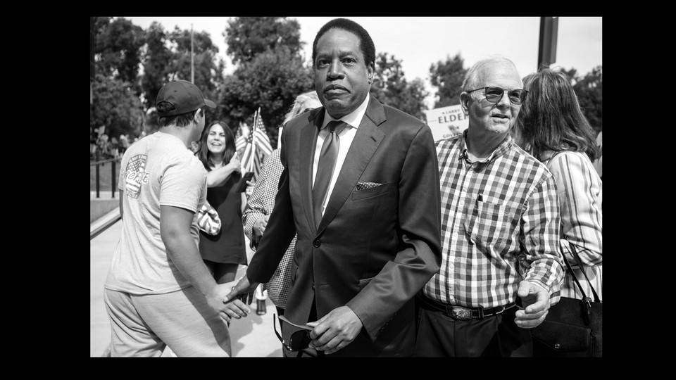 black-and-white photo of Larry Elder in a small crowd