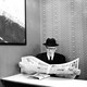 An elderly man wearing a hat and glasses reading a newspaper