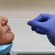 A nurse inserts a swab into a person's nose to test them for a virus.