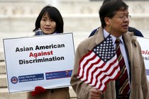 Two Asians hold signs opposing racial discrimination in college admissions outside the Supreme Court