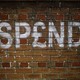 Graffiti on a brick wall in the U.K. spells out "SPEND."