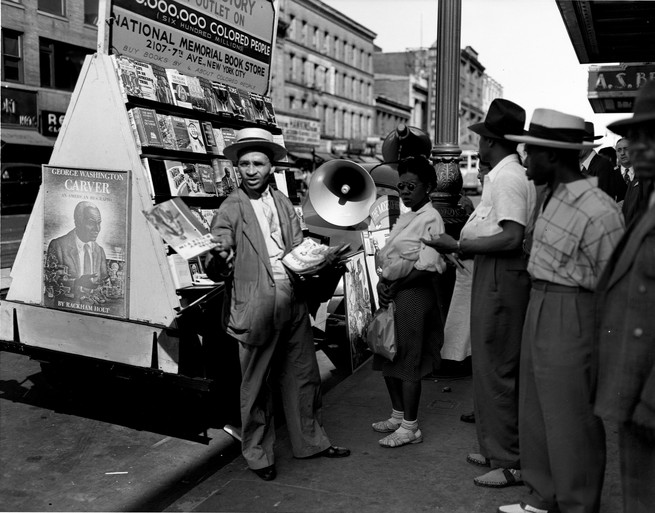 A vendor shows his wares at a bookstall on 125th Street in Harlem, New York, in June 1943.
