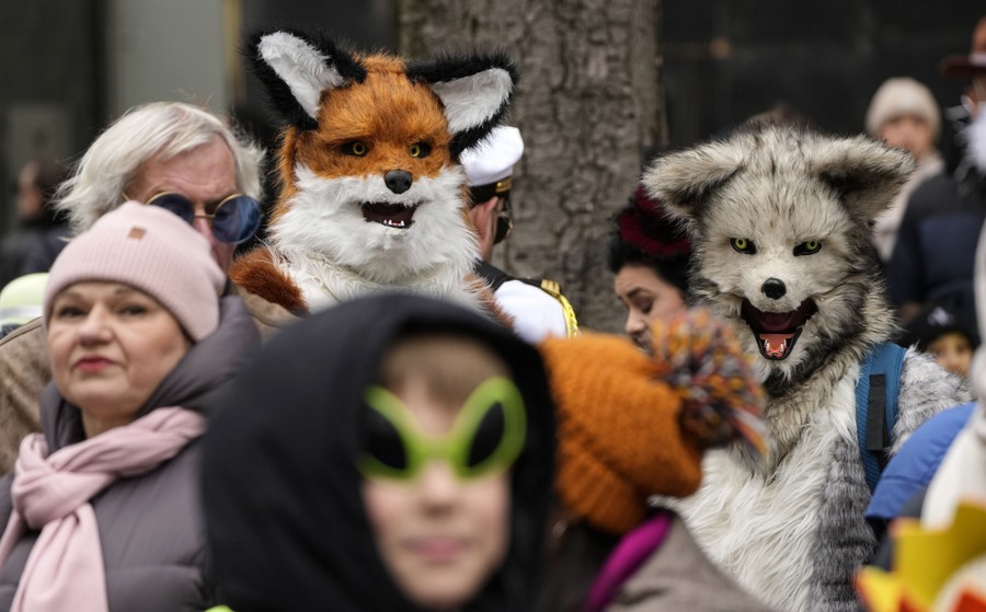 Two people wearing furry costumes stand in a crowd of people.
