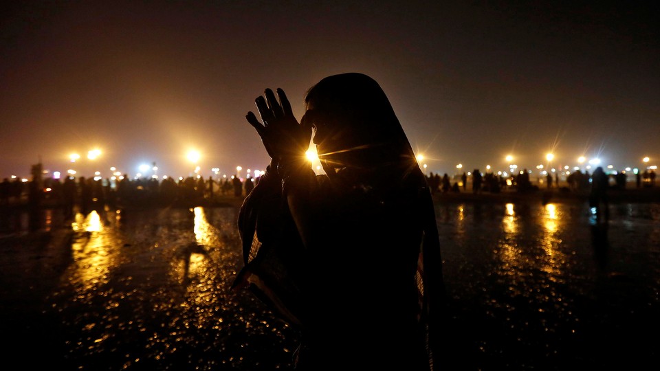 A Hindu pilgrim offers prayers after taking a dip in the Ganges river.