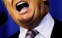 The lower half of Donald Trump's face and neck, showing his mouth open behind a microphone