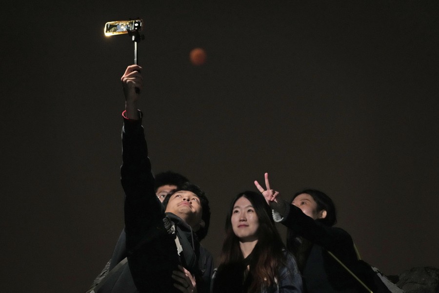 Four people take a selfie, with the moon above them.