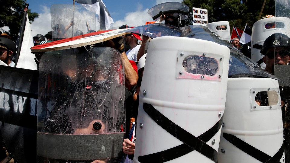 White nationalists shelter behind shields, displaying the Southern Nationalist flag.