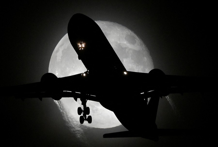 An aircraft passes in front of the moon.