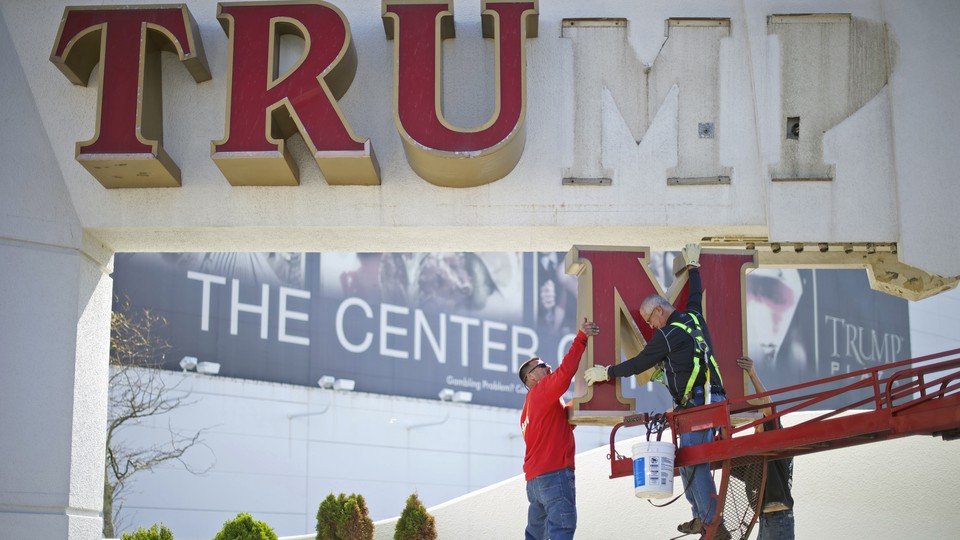 A "Trump" sign is taken down from a building