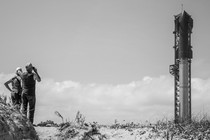 A pair of onlookers gaze at SpaceX's Starship system, which stands upright on its launchpad on the coast of South Texas.