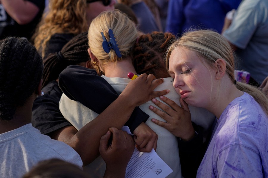 A crowd of people stands together, embracing each other.