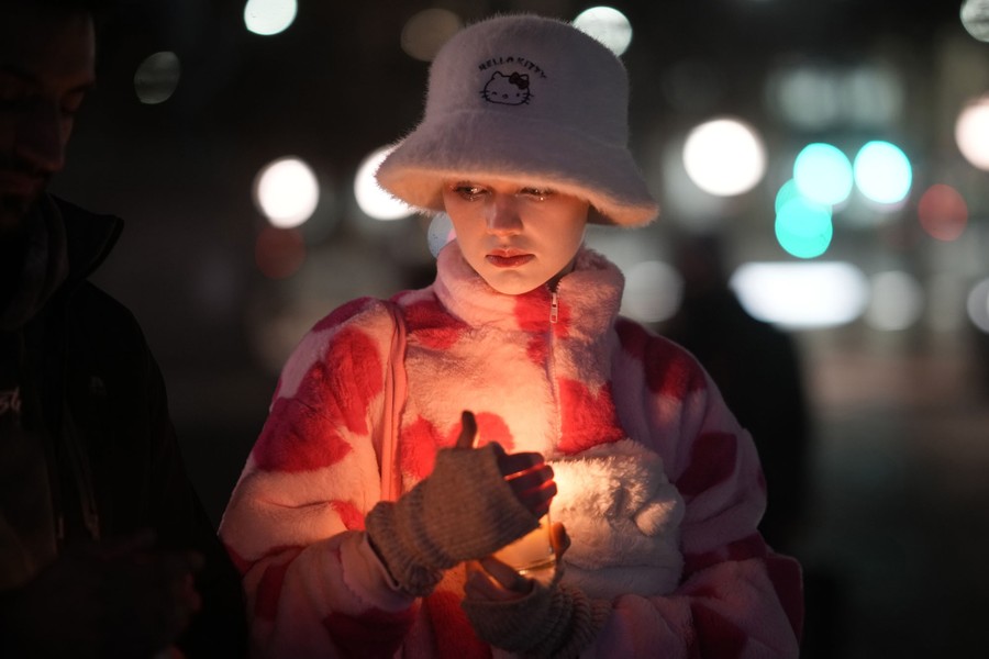 A person stands outside, holding a candle.