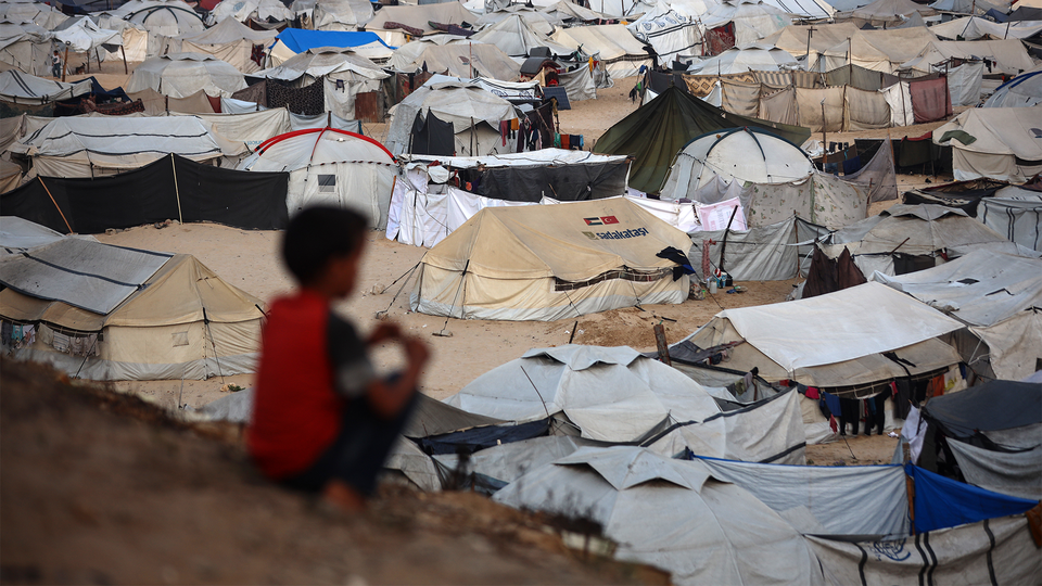 A child sits near tents