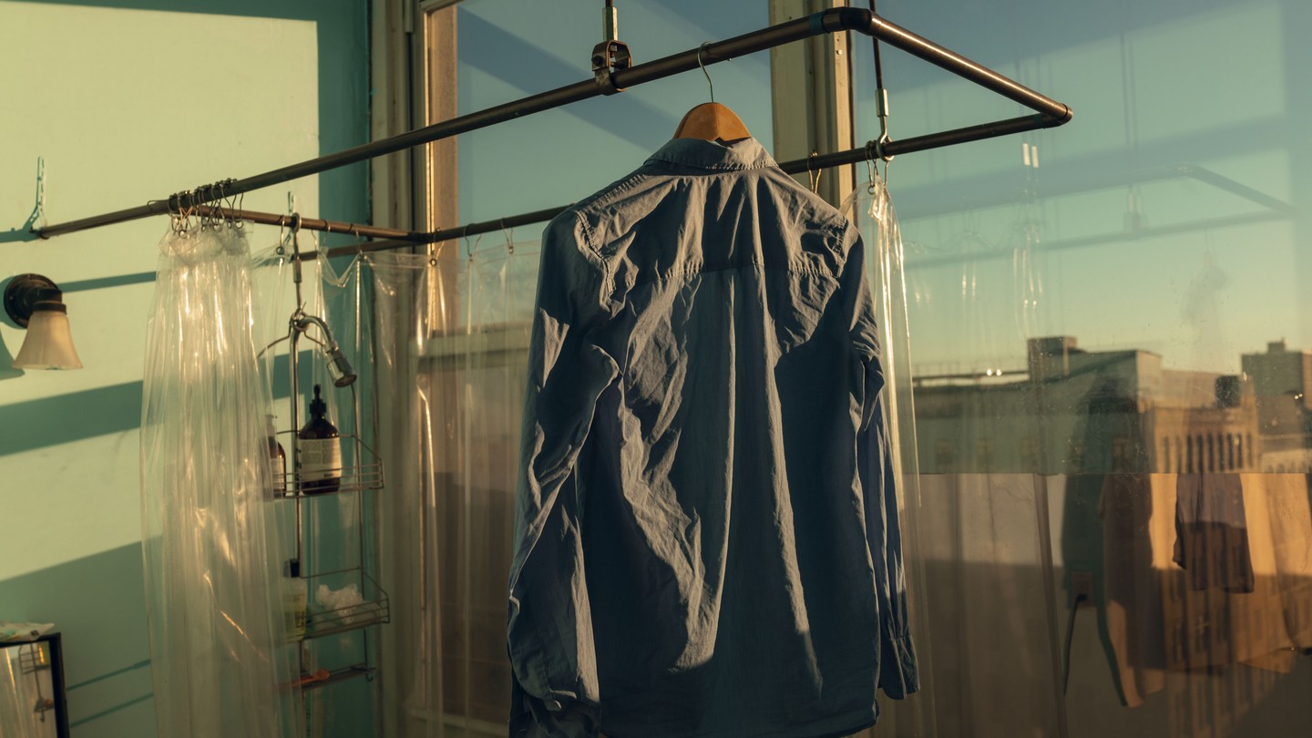 A shirt hanging in golden light before a big window showing a blue sky and a cityscape