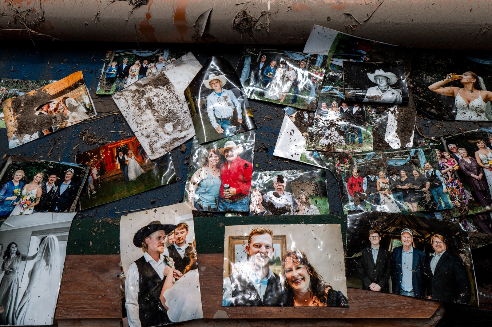 A collection of family photographs, dirtied and recently wet, lie spread out on a table.