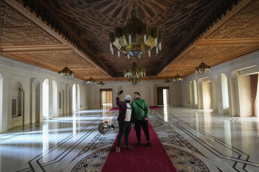 Two people take a selfie in an empty palace hall.