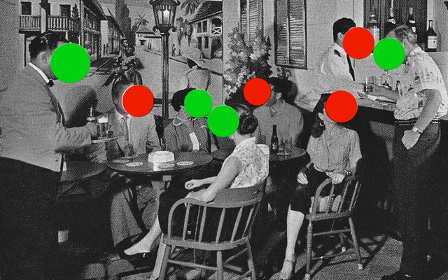 A black-and-white photograph of adults sitting around a restaurant table. Each person has either a red or green dot covering their face.