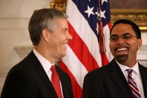 Arne Duncan and John King smile at one another