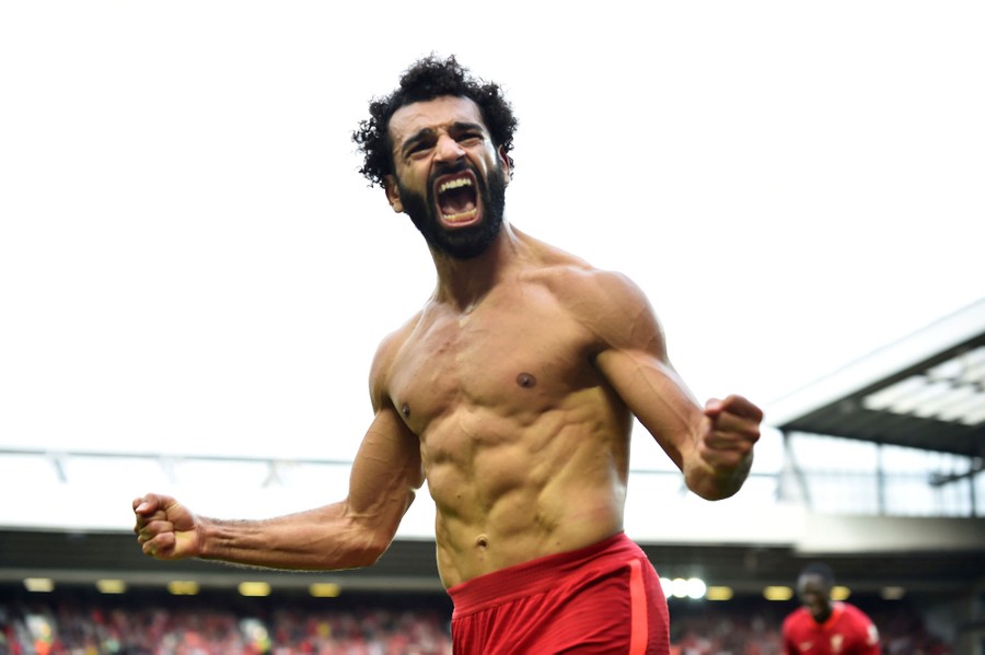 A shirtless soccer player celebrates after scoring a goal.
