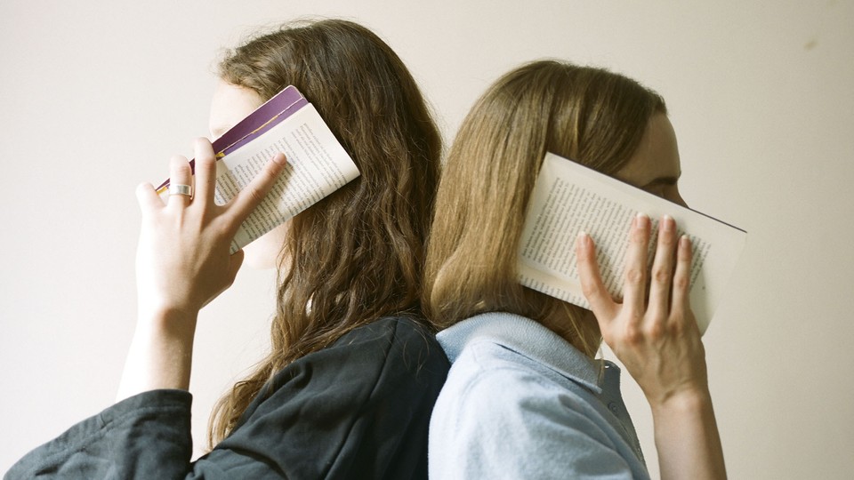 Two people holding books to their ears like phones