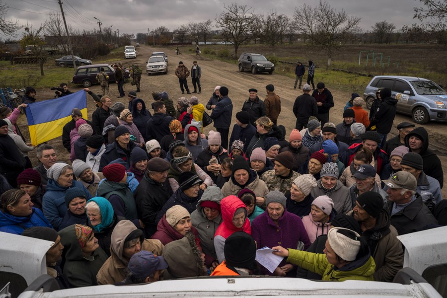 Civilians gather in a crowd around a vehicle where food is being distributed.