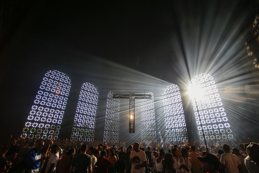 Sunlight streams into the interior of a basilica, as people stand and pray inside.