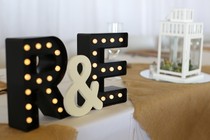 A decoration featuring a couple's initials sits on a table at a wedding reception.