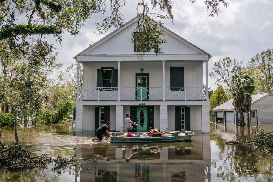 People wade through water in a flooded neighborhood.